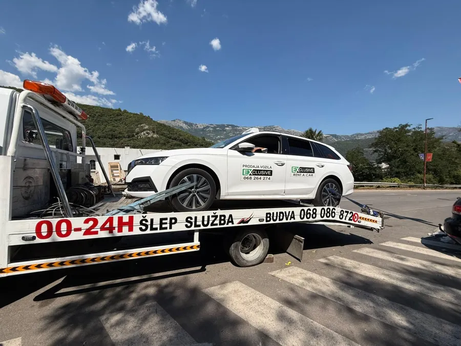 Bijela Škoda na platformi šlep vozila M&M ispred budvanskih planina