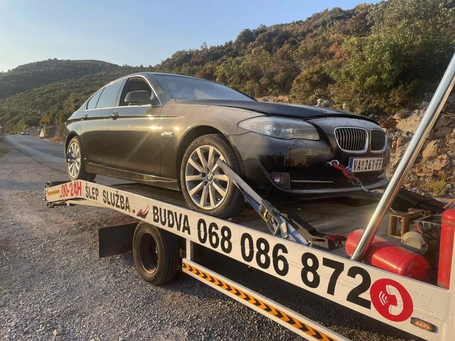 Crni BMW serije 5 utovaren na platformu šlep vozila